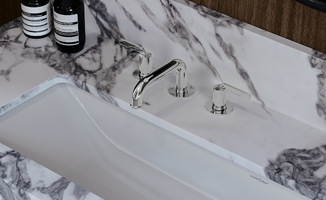 Chrome bathroom sink faucet with a marble sink.
